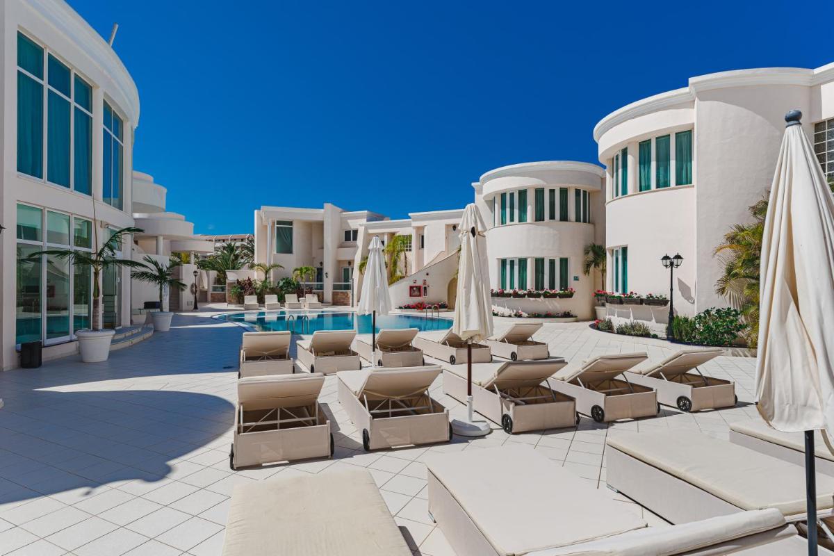 un complejo con piscina, tumbonas y sombrillas en Flamingo Suites Boutique Hotel, en Adeje