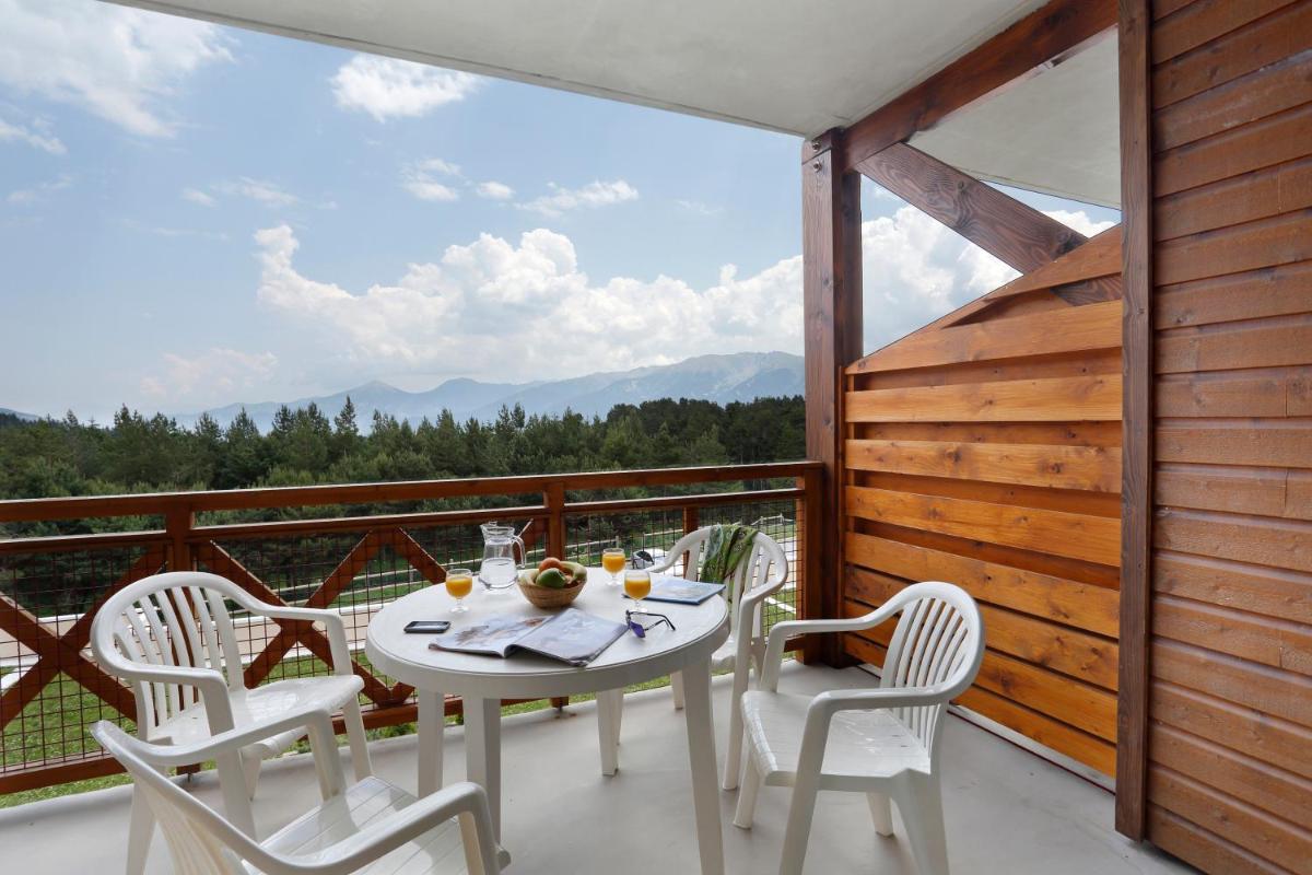 une table et des chaises sur un balcon avec vue dans l'établissement Vacancéole - Appart'Vacances Pyrénées 2000, à Bolquère-Pyrénées 2000