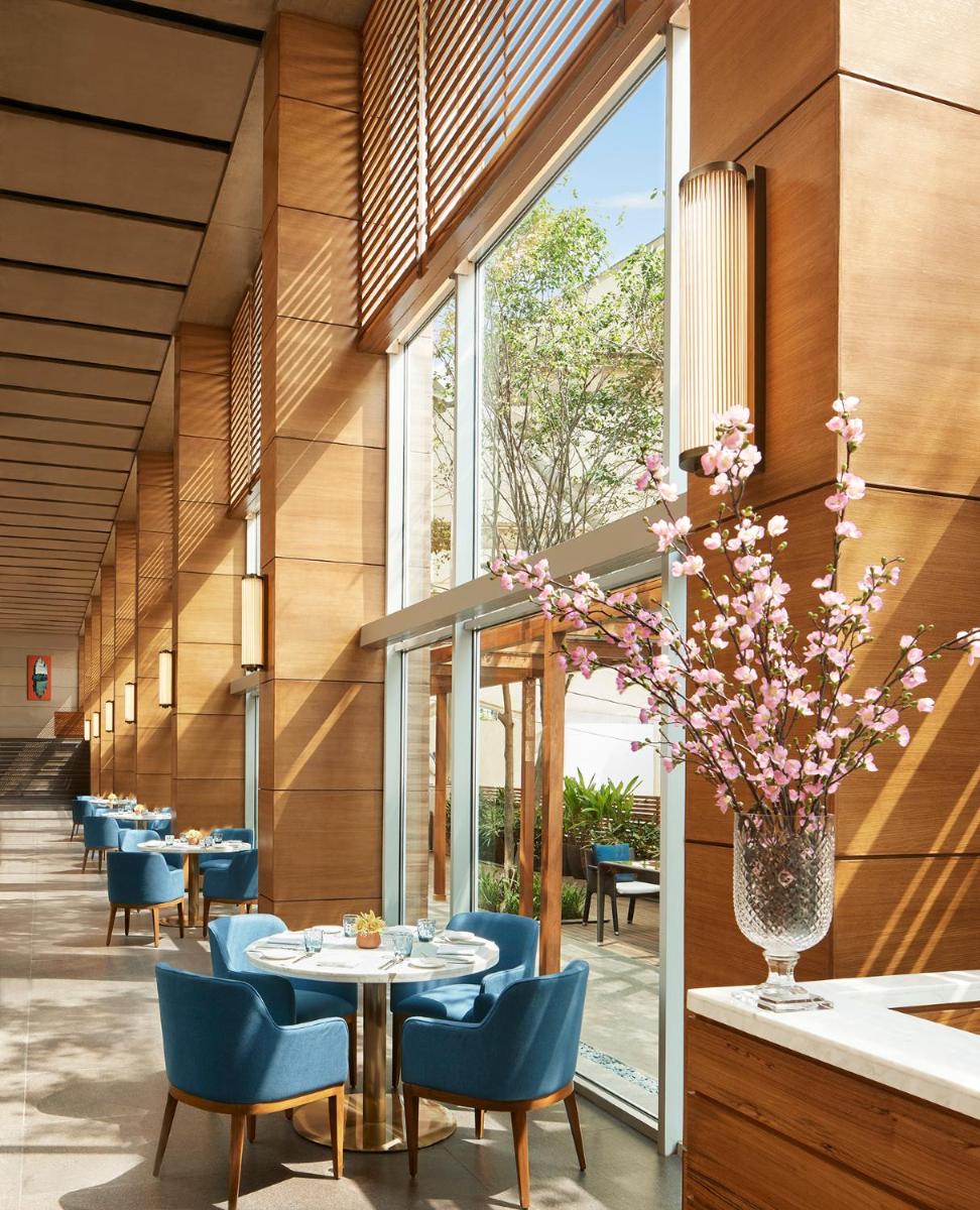 a restaurant with blue chairs and a table with a vase of flowers at Taj City Centre New Town, Kolkata in Kolkata a restaurant with blue chairs and a table with a vase of flowers at Taj City Centre New Town, Kolkata in Kolkata