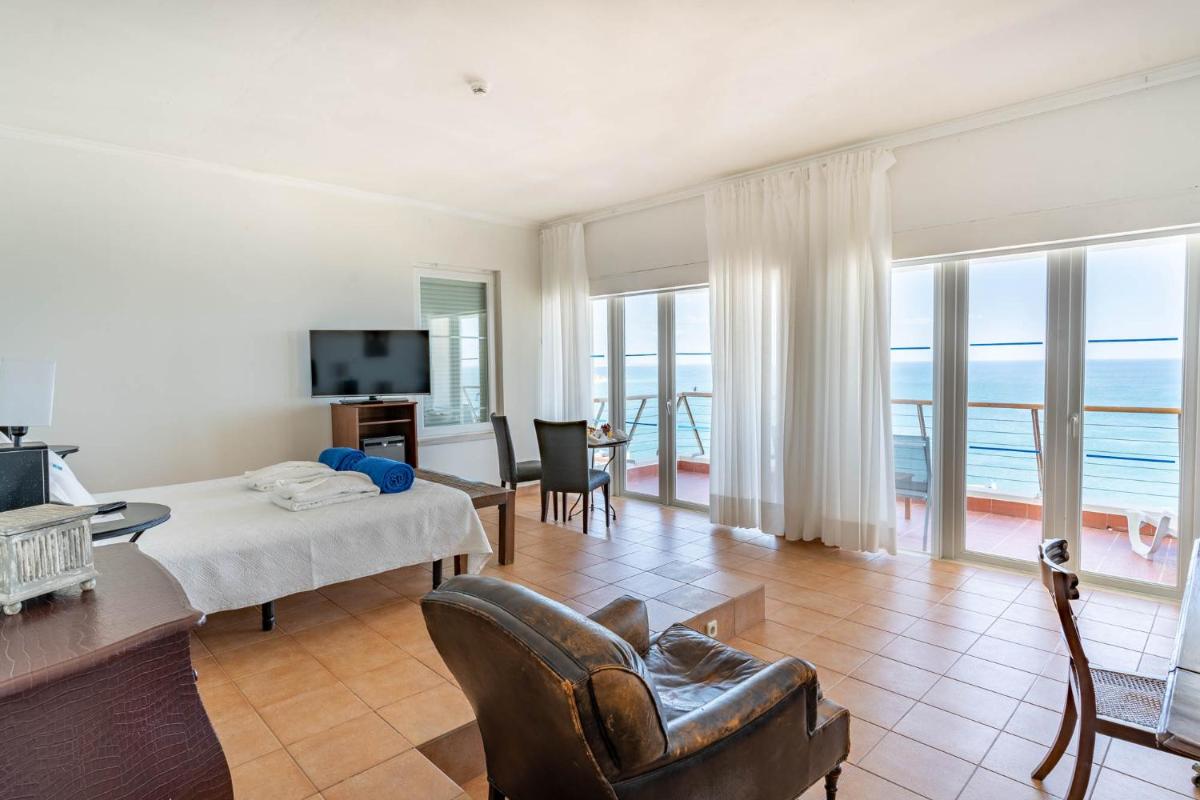 uma sala de estar com uma cama, uma mesa e cadeiras em Boa Vista Hotel & Spa - Adults Only em Albufeira