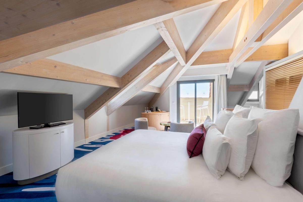 une chambre avec un grand lit blanc et une télévision dans l'établissement Eden Rose Grand Hotel BW Premier Collection, à Bormes-les-Mimosas