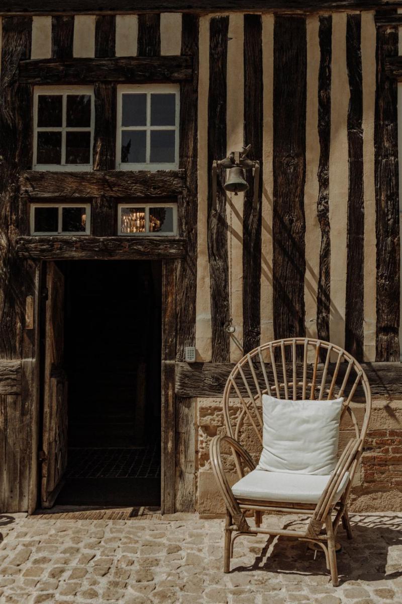une chaise assise devant un bâtiment dans l'établissement Les Manoirs des Portes de Deauville - Small Luxury Hotel Of The World, à Deauville