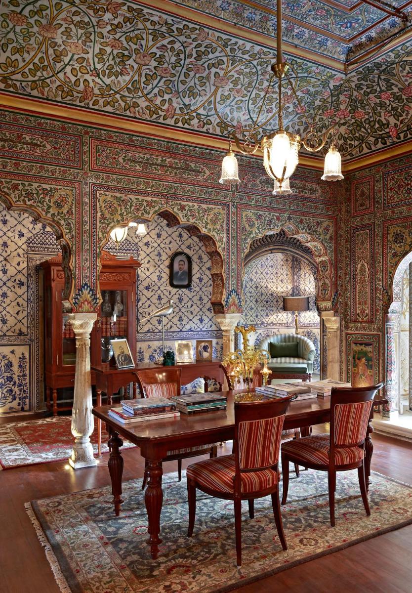 a dining room with a wooden table and chairs at Samode Haveli in Jaipur