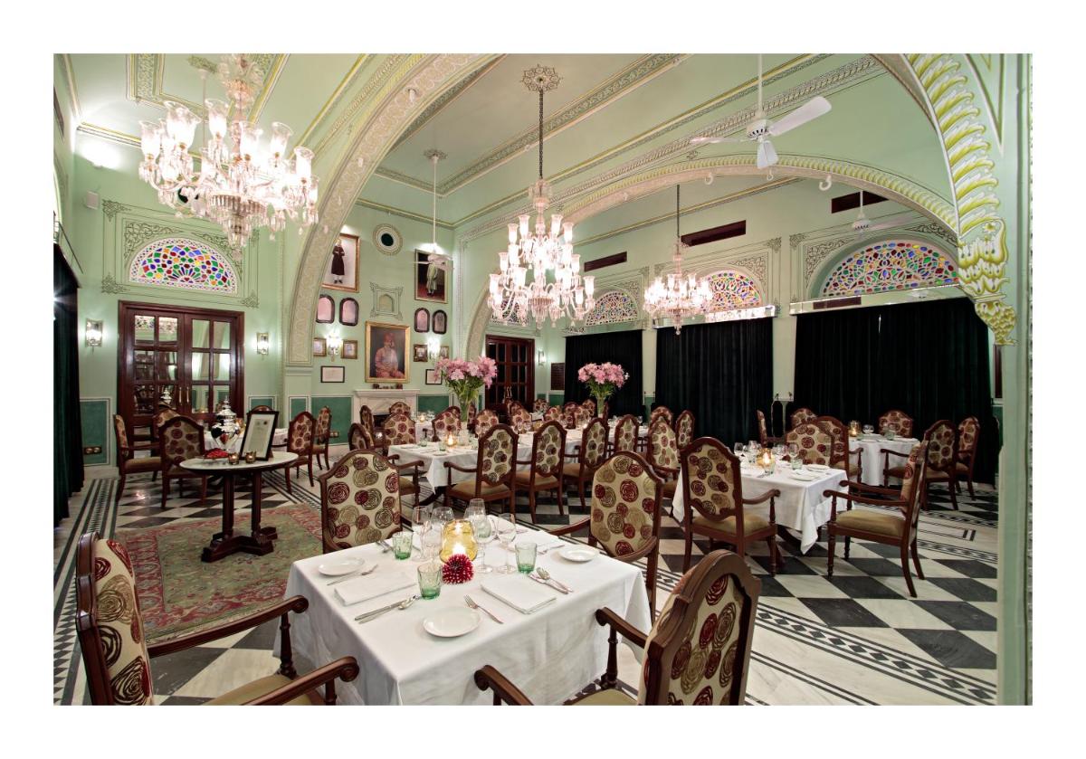 a dining room with white tables and chairs and chandeliers at Samode Haveli in Jaipur
