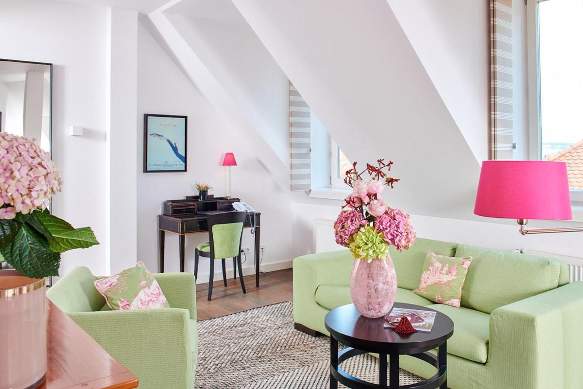 ein Wohnzimmer mit grünen Stühlen und einer Vase mit Blumen auf dem Tisch in der Unterkunft Hotel Goliath am Dom in Regensburg + 37 Fotos