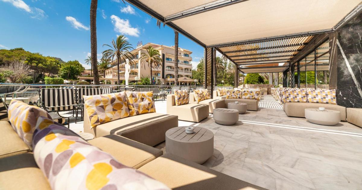 un patio con sofás y sillas y un edificio en Hotel Serrano Palace, en Cala Ratjada