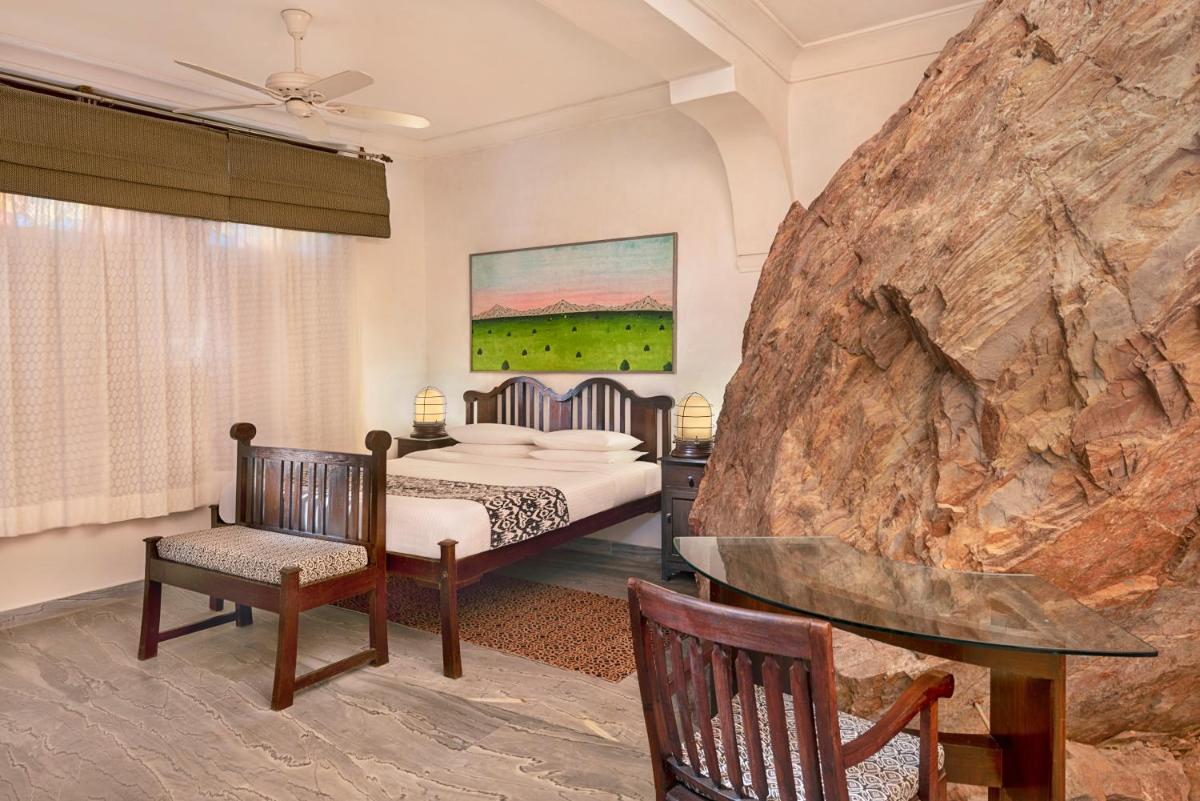 a bedroom with a bed and a large rock at Neemrana Fort-Palace in Neemrana