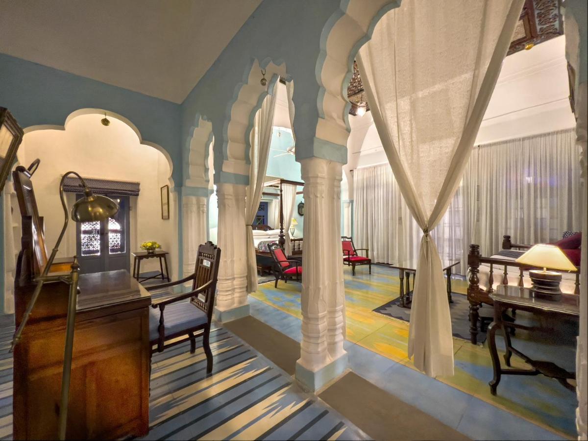 a living room with white columns and a dining room at Neemrana Fort-Palace in Neemrana
