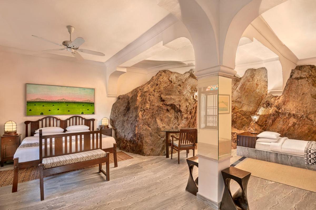 a bedroom with two beds and a rock wall at Neemrana Fort-Palace in Neemrana