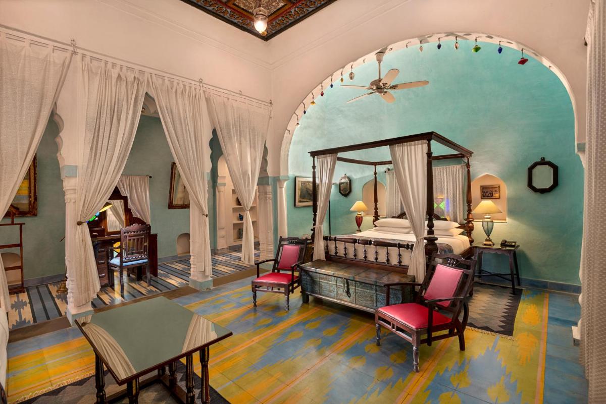 a bedroom with a bed and a table and chairs at Neemrana Fort-Palace in Neemrana