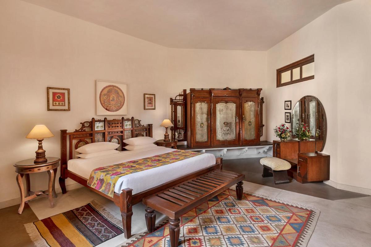 a bedroom with a bed and a wooden cabinet at Neemrana Fort-Palace in Neemrana