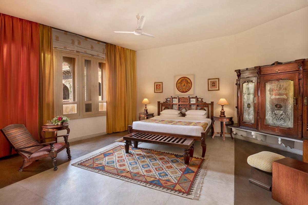 a bedroom with a bed and a couch and a chair at Neemrana Fort-Palace in Neemrana