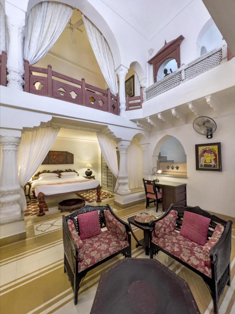 a large room with a bed and two chairs at Neemrana Fort-Palace in Neemrana