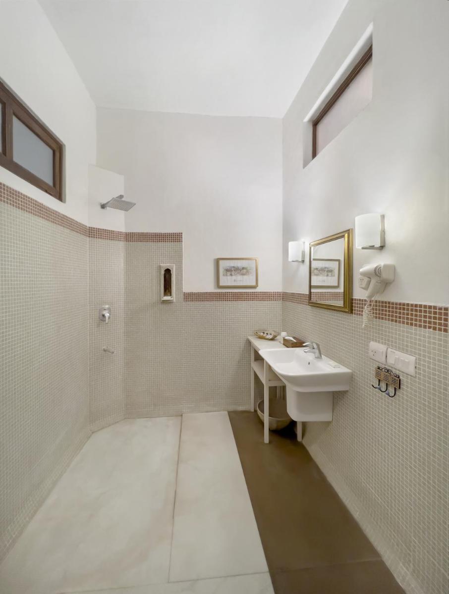 a white bathroom with a sink and a mirror at Neemrana Fort-Palace in Neemrana
