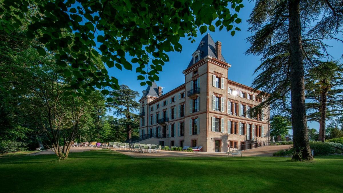 un bâtiment avec une tour au sommet d'une pelouse dans l'établissement Château de Fiac - Luxurious Hôtel & Spa, à Fiac