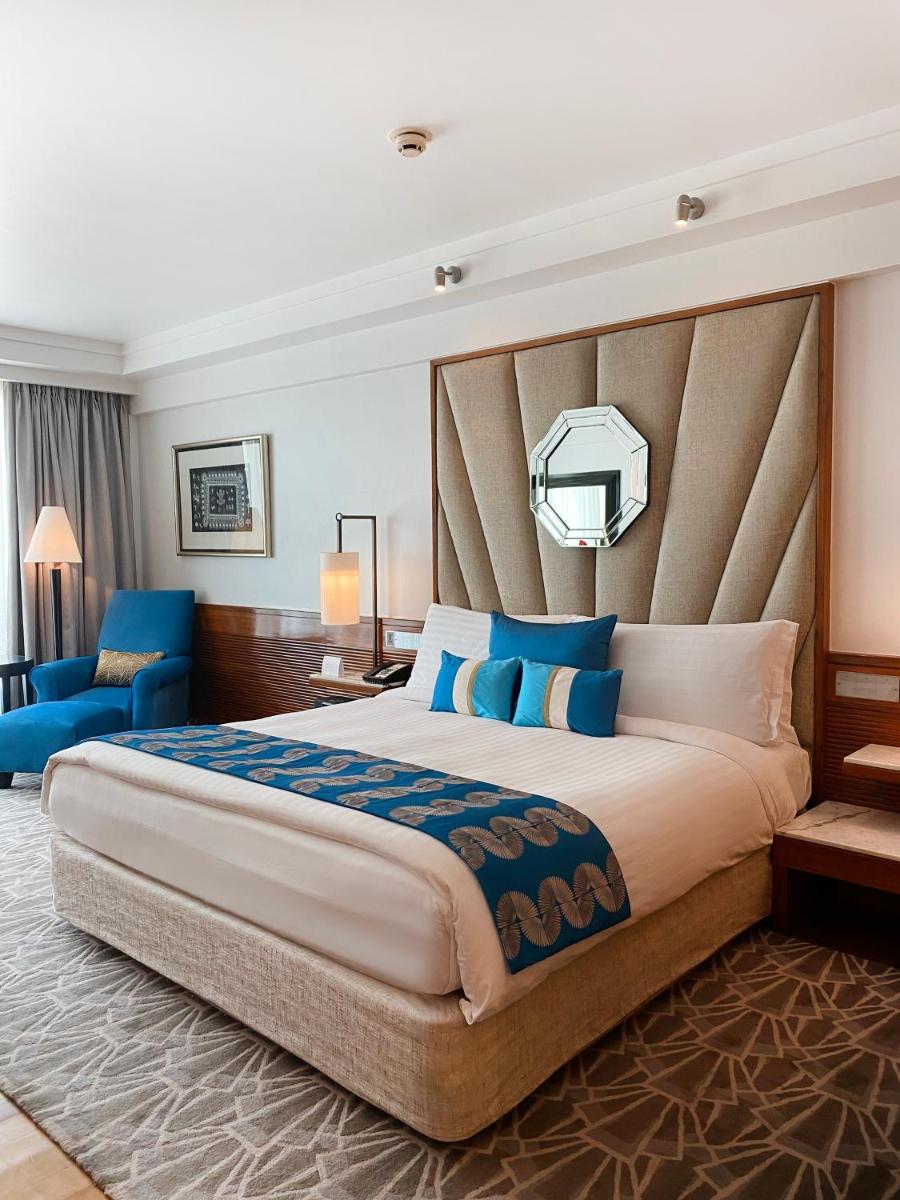 a bedroom with a large bed and a blue chair at InterContinental Marine Drive Mumbai by IHG in Mumbai