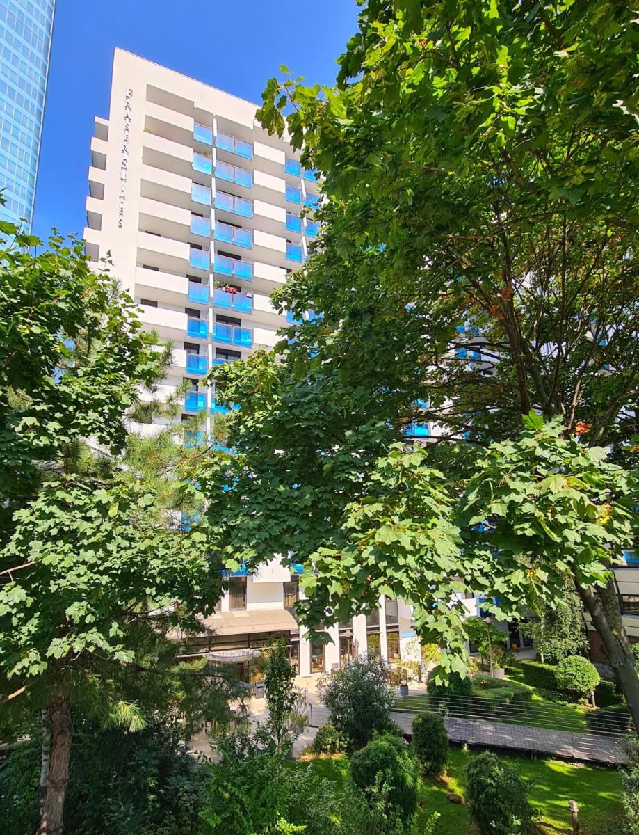 un grand bâtiment blanc avec des arbres devant lui dans l'établissement Fraser Suites Paris La Défense, à Courbevoie