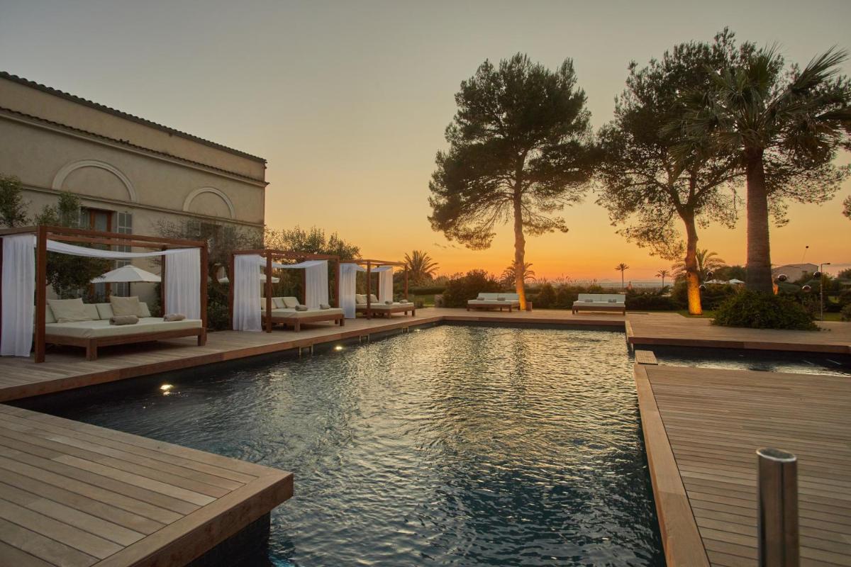 Una piscina con una puesta de sol al fondo en Fontsanta Hotel Thermal & Spa - Adults Only, en Colonia de Sant Jordi
