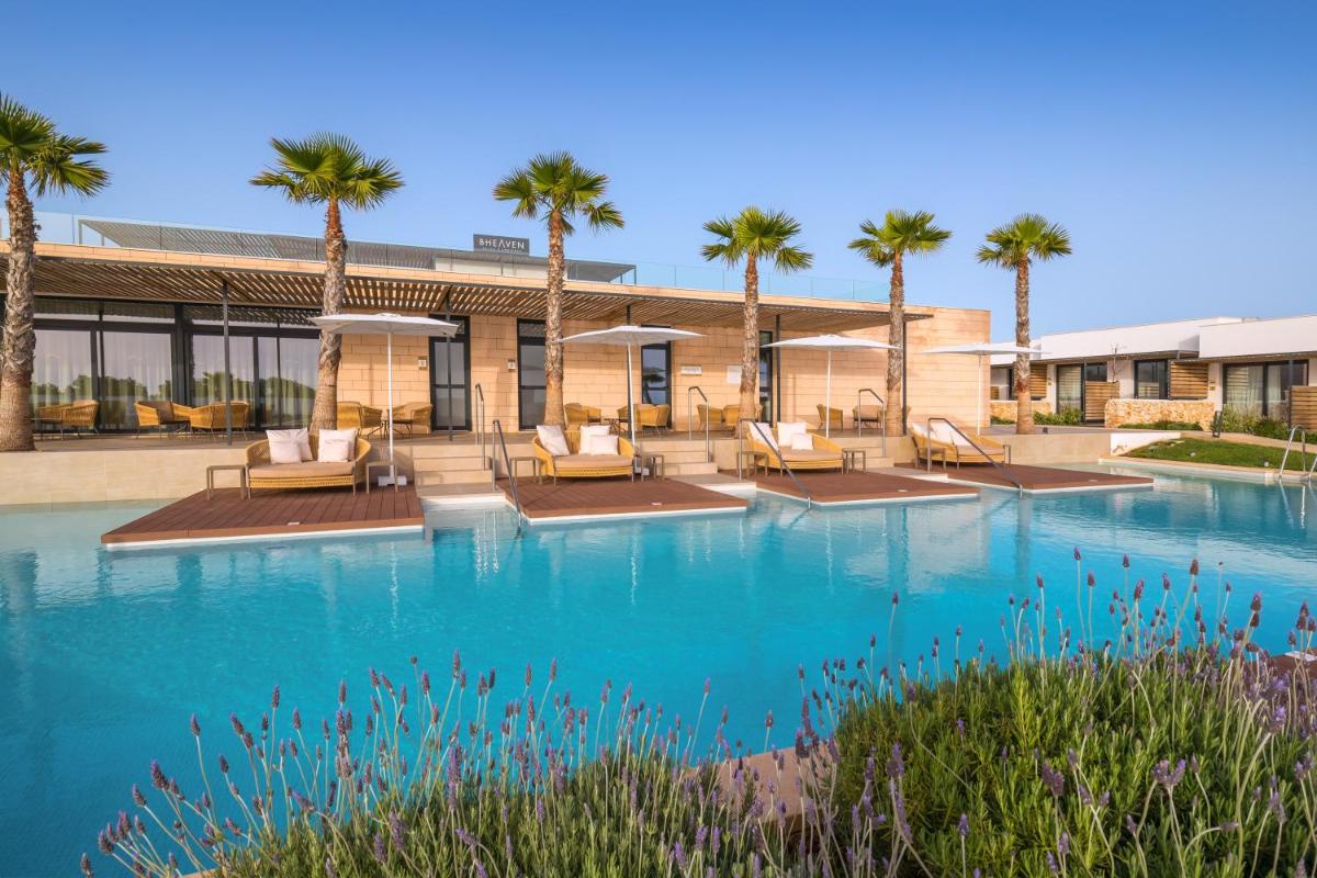 Un complejo con palmeras y piscina. en Barceló Nura, en Sant Lluis