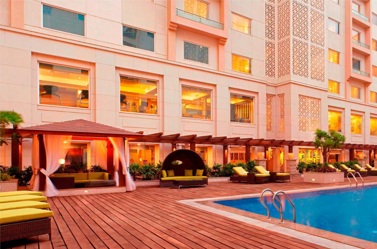 a hotel with a swimming pool in front of a building at Lemon Tree Premier, Delhi Airport in New Delhi a hotel with a swimming pool in front of a building at Lemon Tree Premier, Delhi Airport in New Delhi
