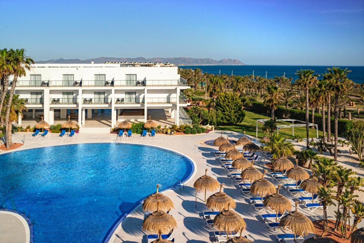 un complejo con piscina, sillas y sombrillas en Hotel Cabogata Jardín, en Retamar