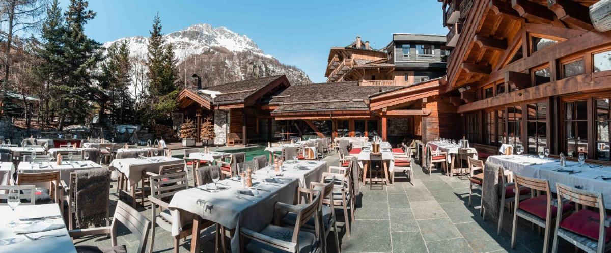 un restaurant avec des tables et des chaises devant un bâtiment dans l'établissement Hôtel LE BLIZZARD, à Val dʼIsère 20 autres photos