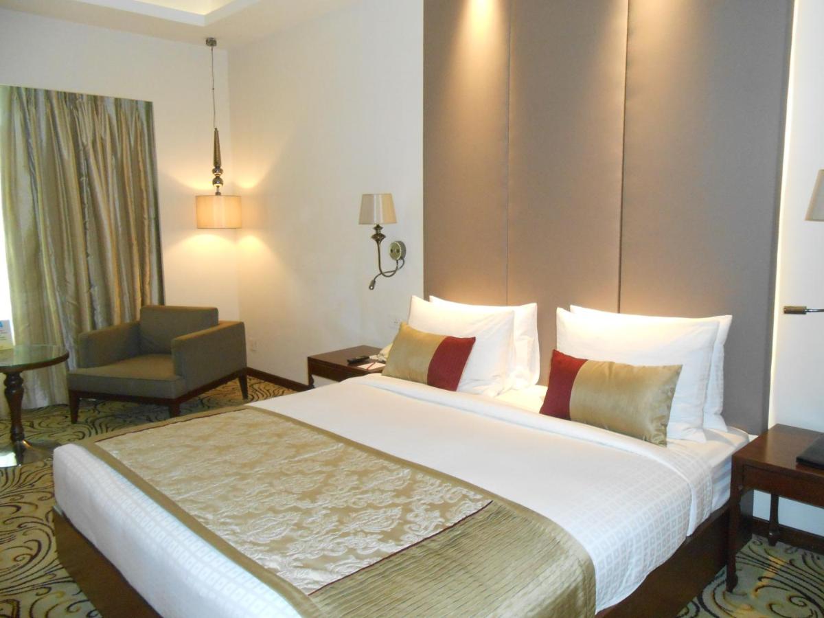 a hotel room with a large bed and a chair at Pride Plaza Hotel, Kolkata in Kolkata
