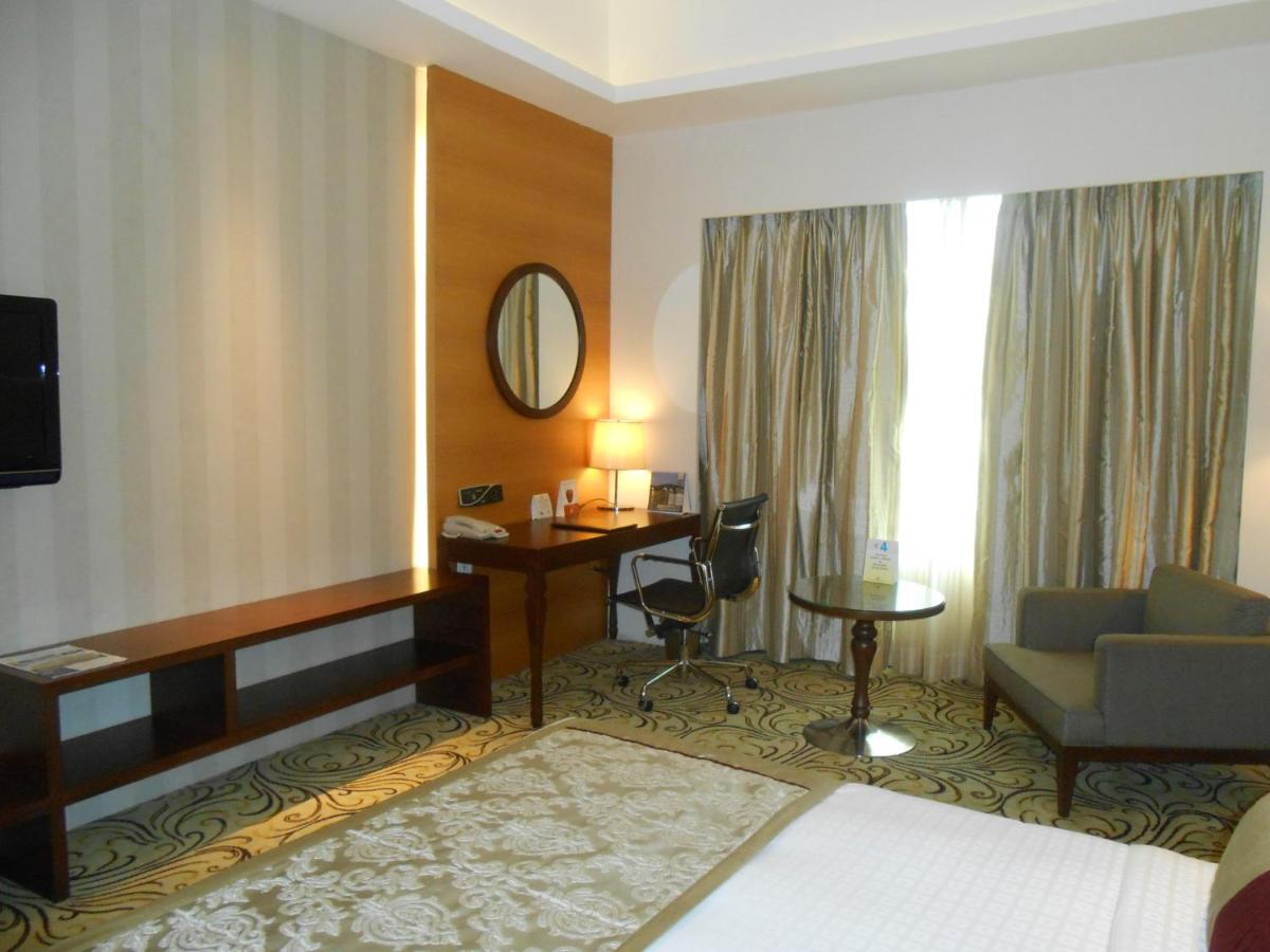 a hotel room with a bed and a desk and a chair at Pride Plaza Hotel, Kolkata in Kolkata