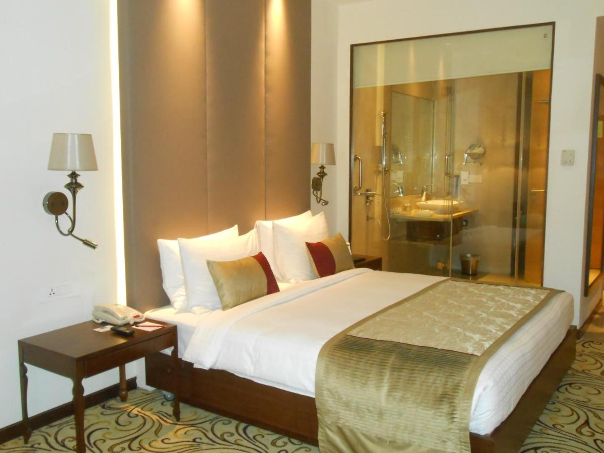 a hotel room with a bed and a shower at Pride Plaza Hotel, Kolkata in Kolkata