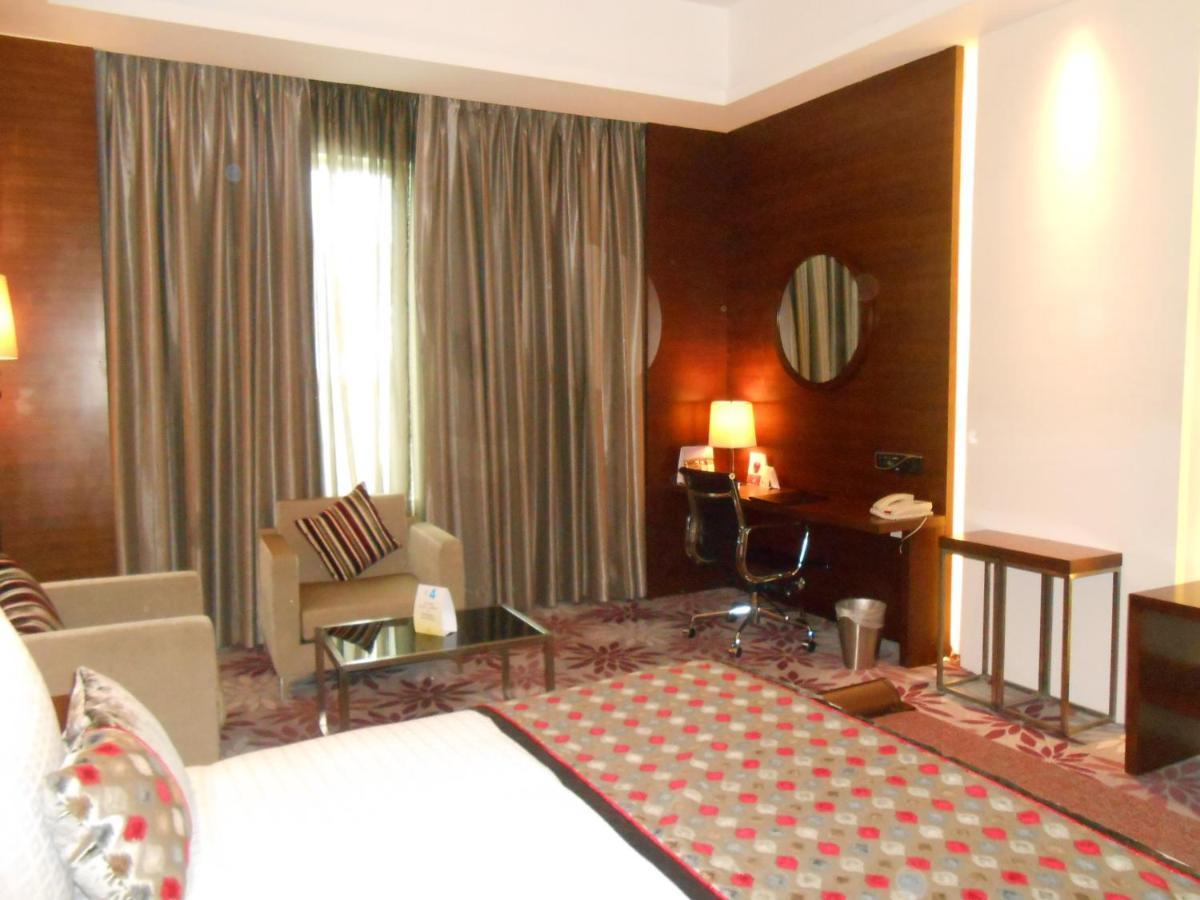 a hotel room with a bed and a living room at Pride Plaza Hotel, Kolkata in Kolkata