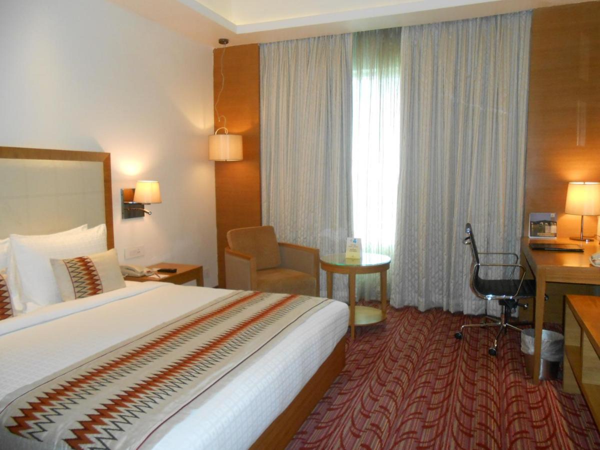 a hotel room with a large bed and a desk at Pride Plaza Hotel, Kolkata in Kolkata