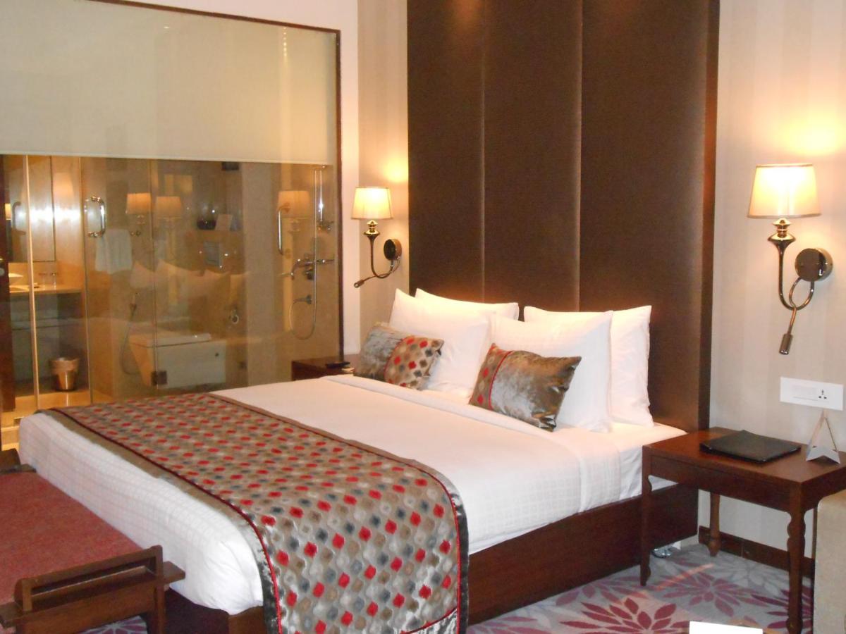 a hotel room with a large bed and a window at Pride Plaza Hotel, Kolkata in Kolkata
