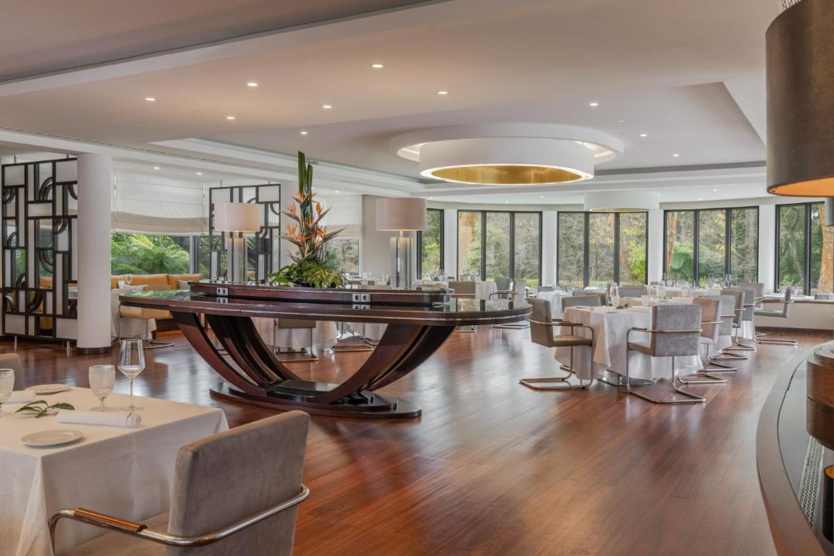 uma sala de jantar com uma mesa grande e cadeiras em Terra Nostra Garden Hotel nas Furnas