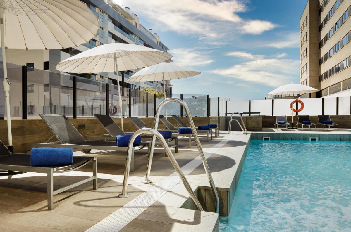Una piscina en la parte superior de un edificio con sillas y sombrillas. en Gran Hotel Luna de Granada, en Granada