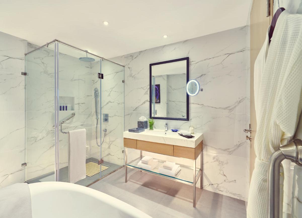 a bathroom with a shower and a sink and a mirror at Vivanta Navi Mumbai Turbhe in Navi Mumbai