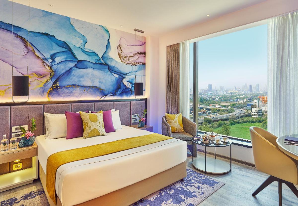 a bedroom with a large bed and a large window at Vivanta Navi Mumbai Turbhe in Navi Mumbai
