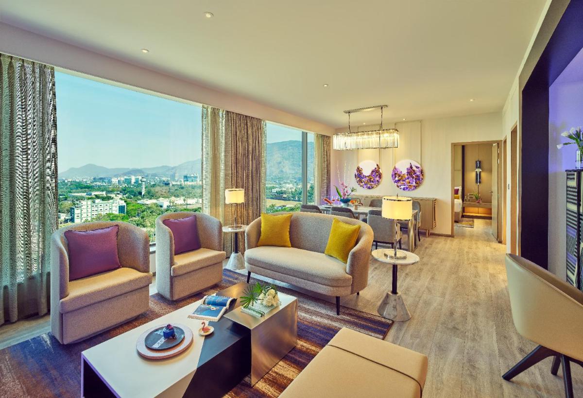 a living room with furniture and a large window at Vivanta Navi Mumbai Turbhe in Navi Mumbai