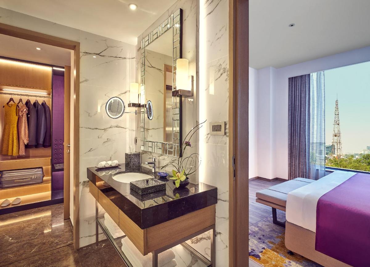 a bathroom with a bed and a sink and a mirror at Vivanta Navi Mumbai Turbhe in Navi Mumbai
