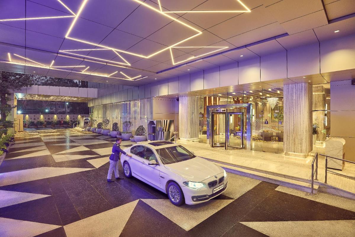 a woman standing next to a car in a building at Vivanta Navi Mumbai Turbhe in Navi Mumbai