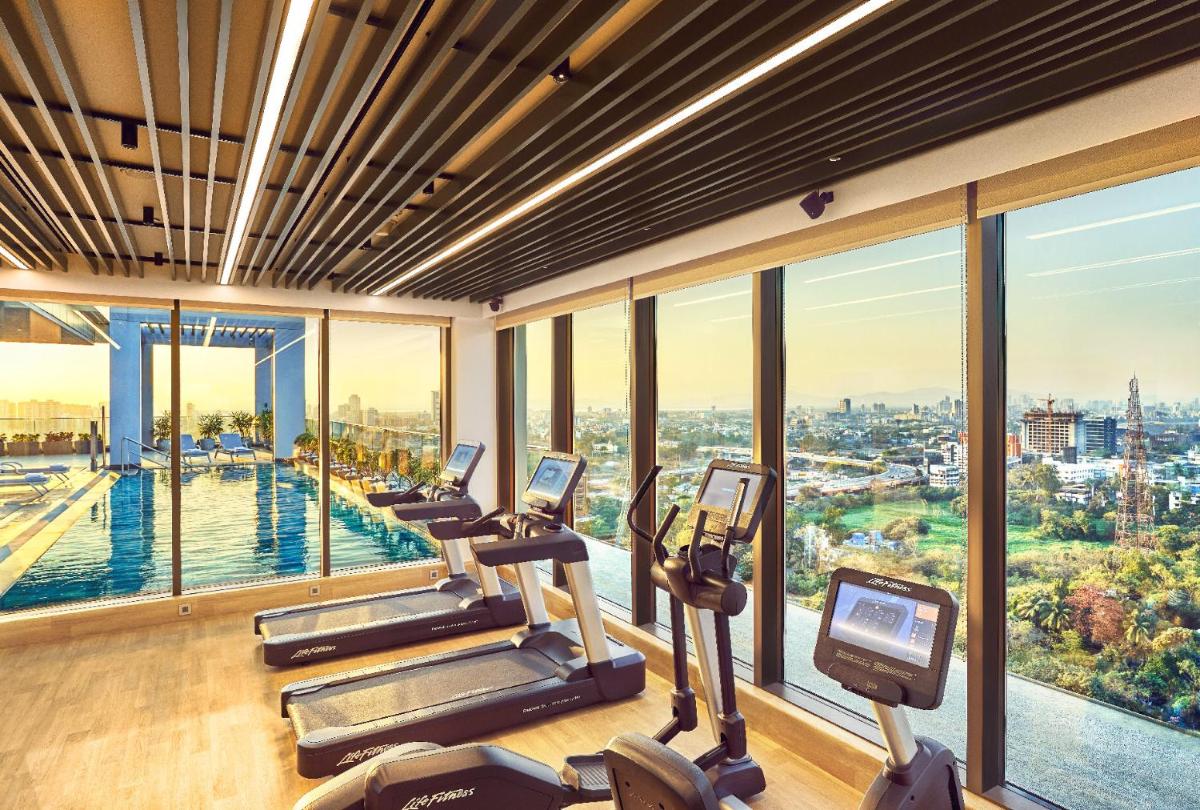 a gym with cardio machines and a view of the city at Vivanta Navi Mumbai Turbhe in Navi Mumbai