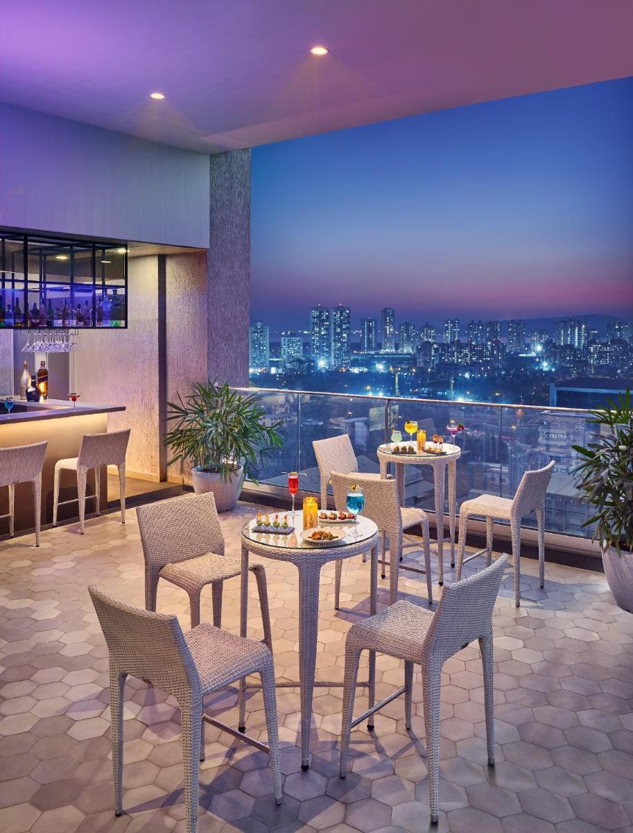 a restaurant with tables and chairs and a view of a city at Vivanta Navi Mumbai Turbhe in Navi Mumbai
