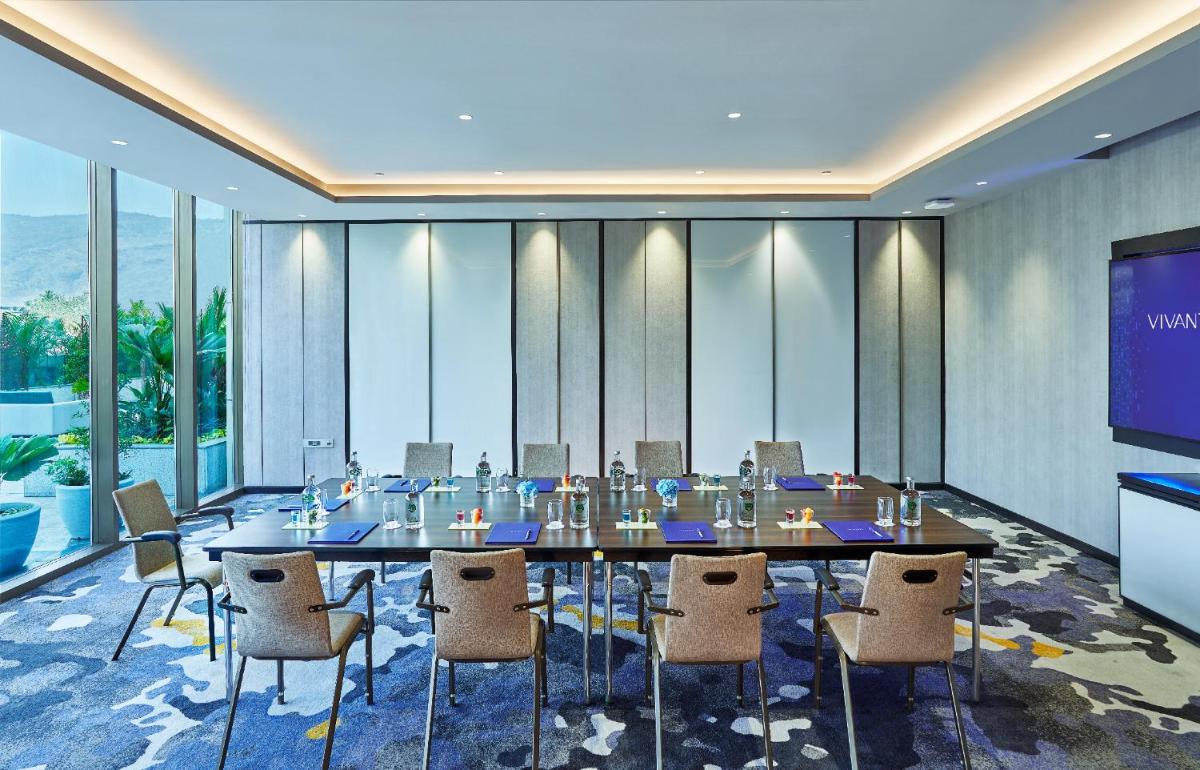 a conference room with a table and chairs and a projection screen at Vivanta Navi Mumbai Turbhe in Navi Mumbai