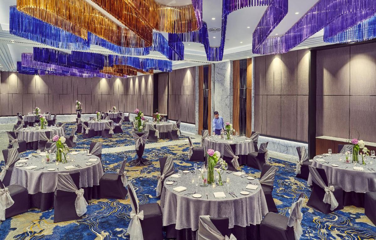 a banquet hall with tables and chairs in a room at Vivanta Navi Mumbai Turbhe in Navi Mumbai