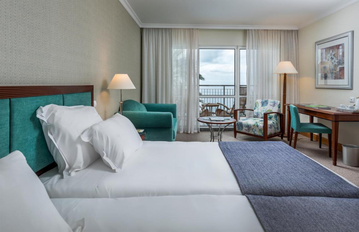 um quarto de hotel com uma cama e uma sala de estar em Pestana Grand Ocean Resort Hotel no Funchal