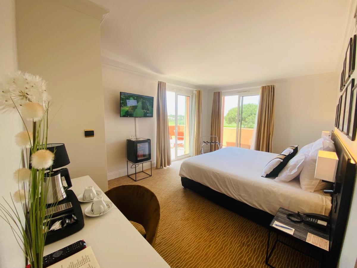 une chambre d'hôtel avec un lit et un bureau avec une télévision dans l'établissement Palmyra Golf Hotel & Spa, au Cap d'Agde