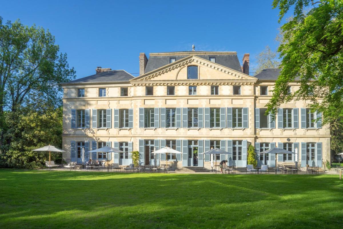 un grand bâtiment avec une pelouse devant dans l'établissement Domaine de Primard - Fontenille Collection, à Guainville