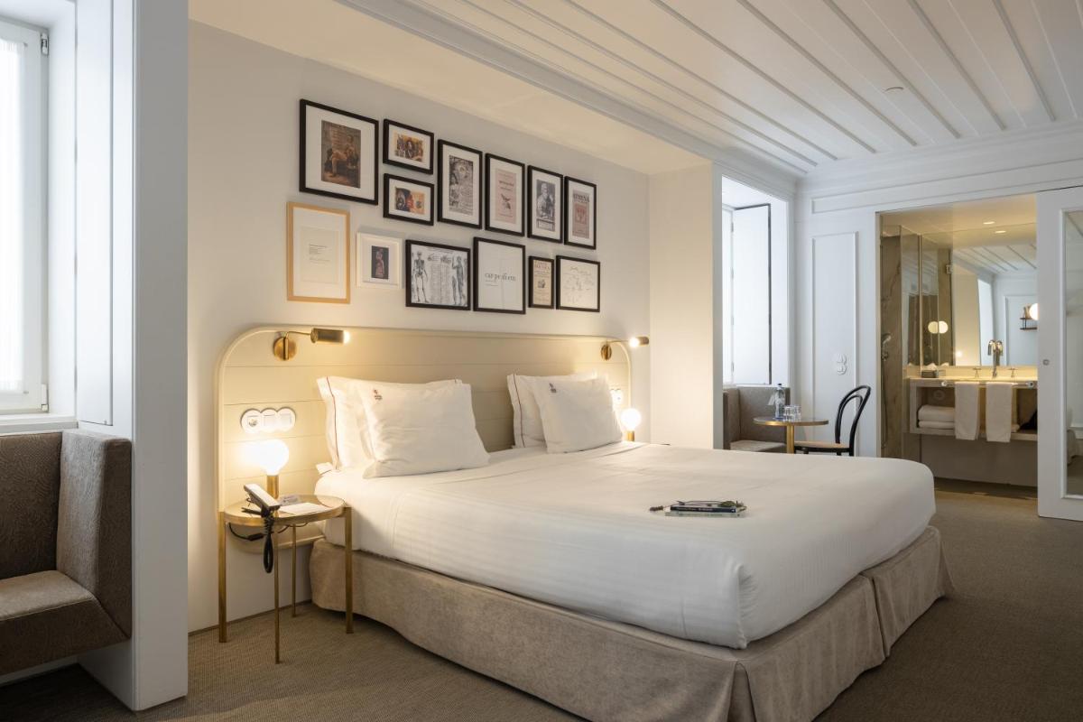 um quarto com uma grande cama branca e quadros na parede em Lisboa Pessoa Hotel em Lisboa