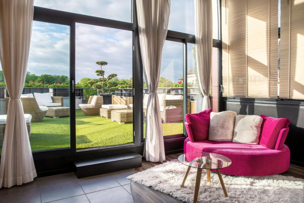 - un salon avec une chaise rose et de grandes fenêtres dans l'établissement Best Western Plus Thionville Centre, à Thionville