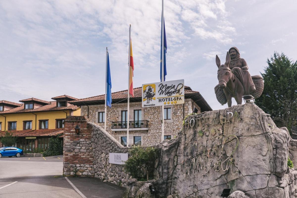 Una estatua de una persona montando a caballo frente a un edificio. en Hotel & Spa María Manuela, en Onís