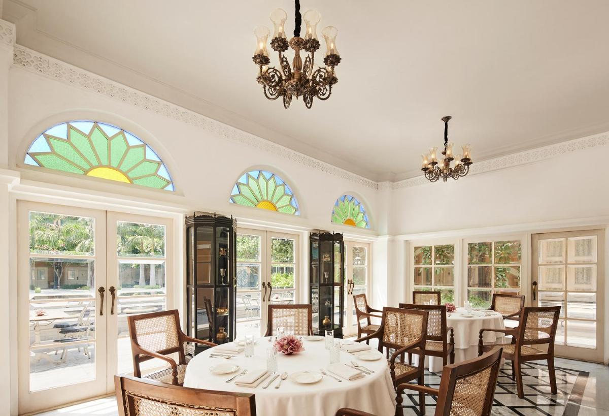 a dining room with tables and chairs and windows at Raajkutir - IHCL SeleQtions in Kolkata